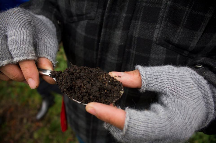 Alan Vergnes tenant une cuillerée de terre de Chamarande – © Yesenia Thibault-Picazo
